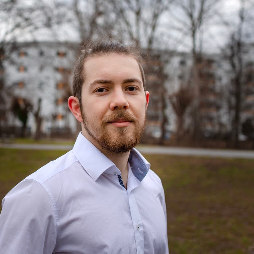 Photo of Jan Sprenger. 
In the background is an urban autumn landscape.